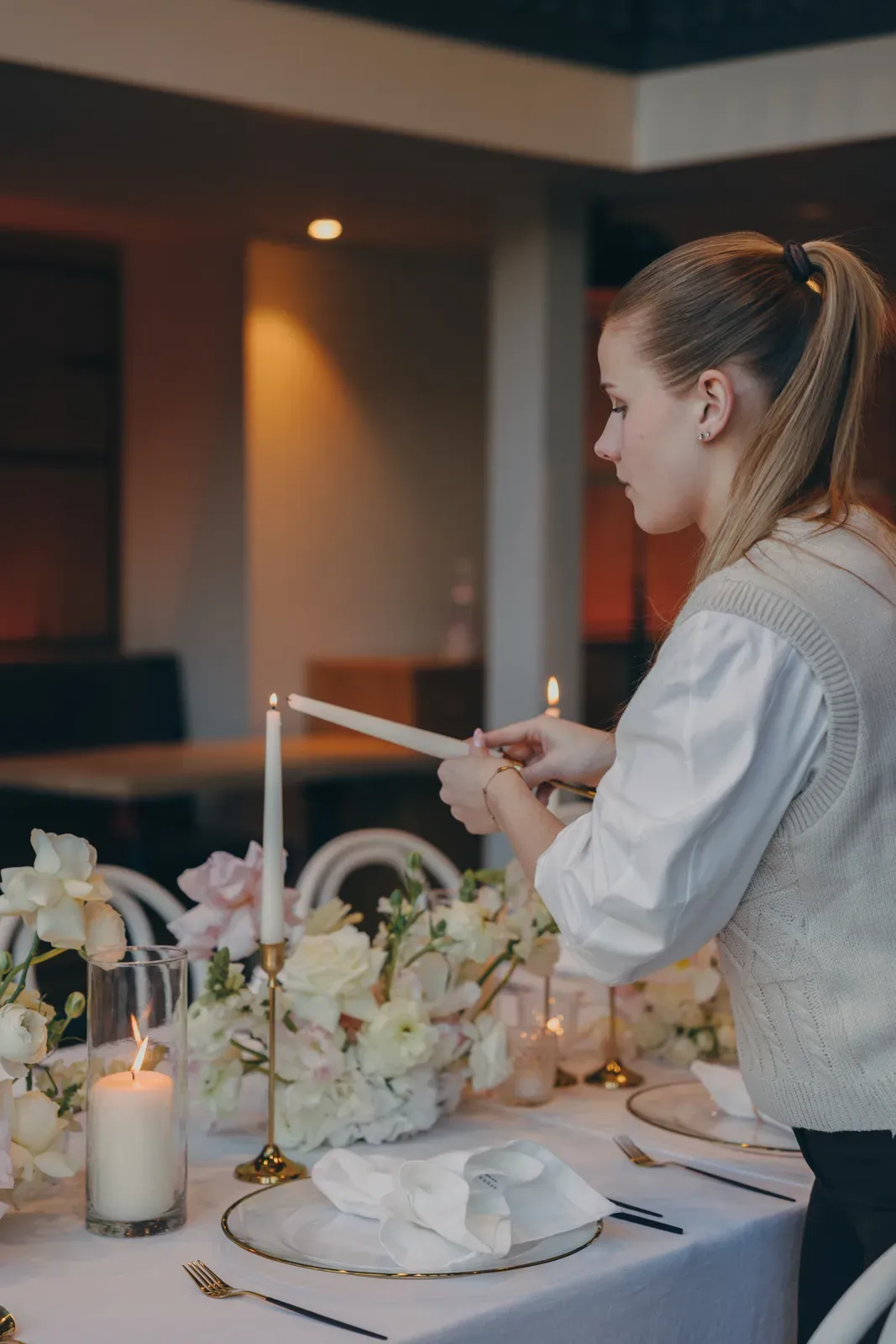 Kerzen werden an einer floral gedeckten Tafel entzündet