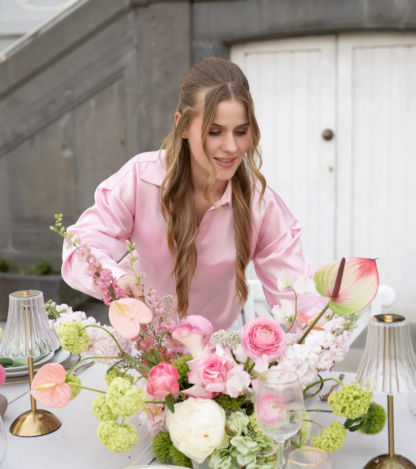 Florale Tischdekoration wird an einer festlich gedeckten Tafel arrangiert